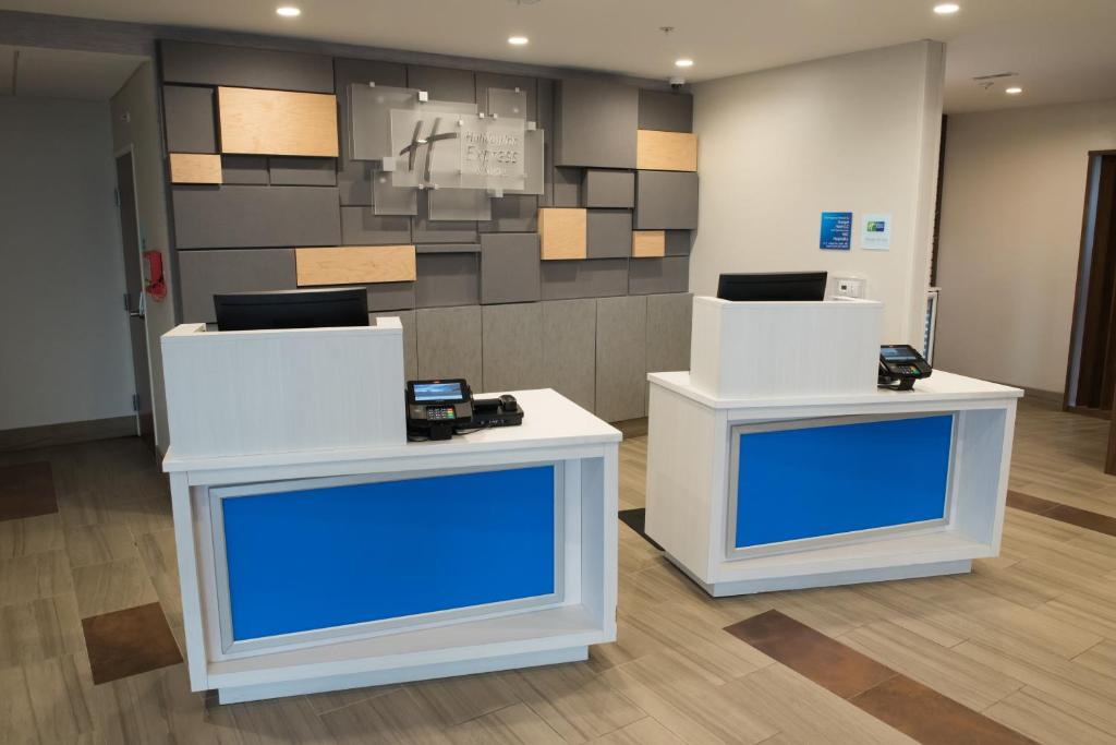 two white tables with blue screens in a room at Holiday Inn Express Hotel & Suites East Lansing by IHG in East Lansing