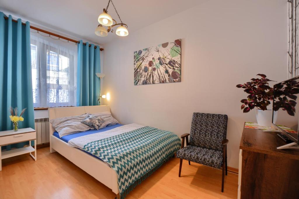a bedroom with a bed and a chair at Mini apartament in Łańcut
