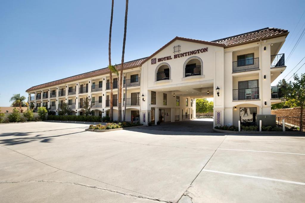 a large white building with a parking lot at Hotel Huntington in Duarte