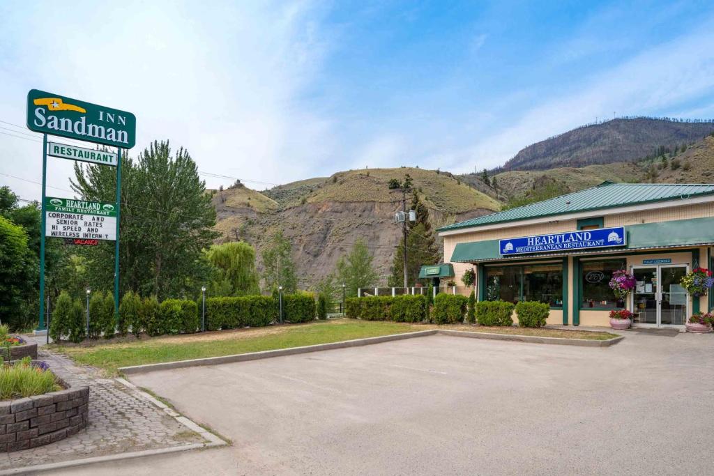 a parking lot in front of a building with a mountain at Sandman Inn Cache Creek in Cache Creek