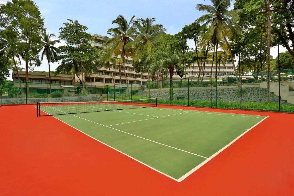 a tennis court in front of a building with palm trees at Radisson Blu Mammy Yoko Hotel in Freetown