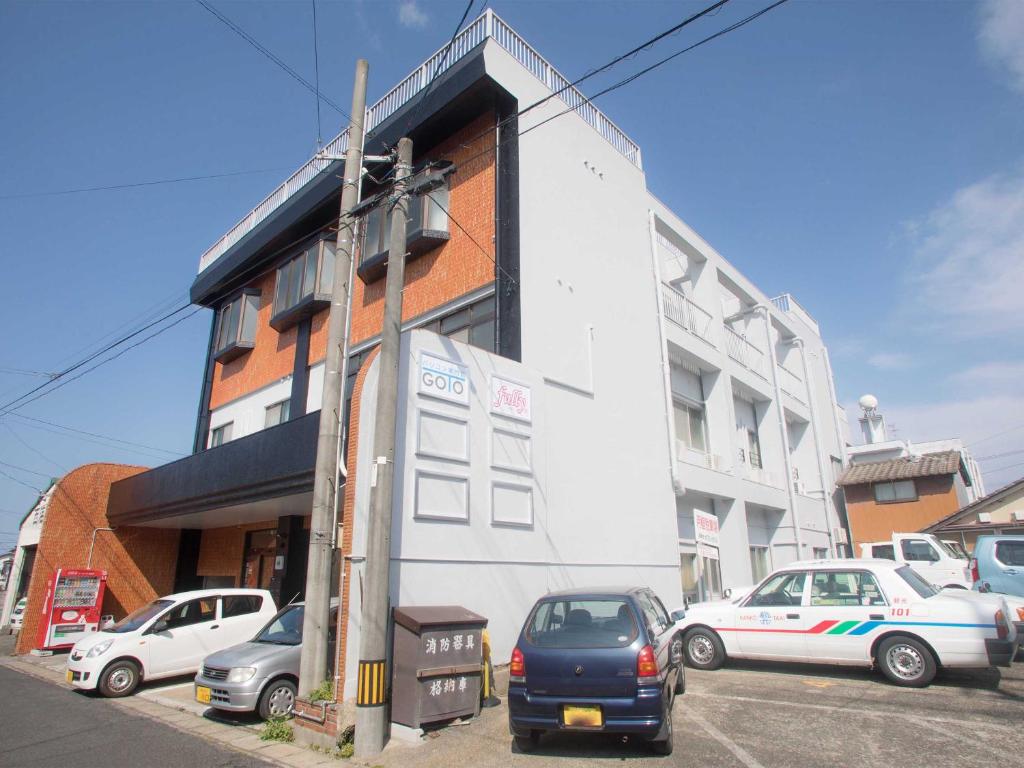 a building with cars parked in front of it at ゲストハウス五島時光 in Goto