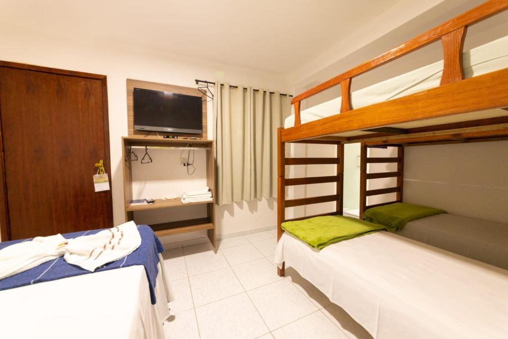 a bedroom with two bunk beds and a television at Pousada Boa Vista in Maragogi