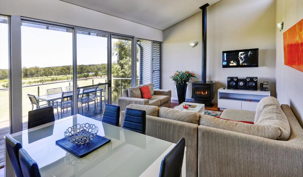 a living room with a table and chairs and a fireplace at Adina Vineyard in Lovedale