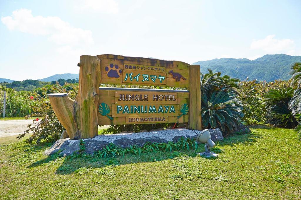 a sign for a jungle hotel in the grass at Iriomotejima-Jungle Hotel Painumaya in Iriomote