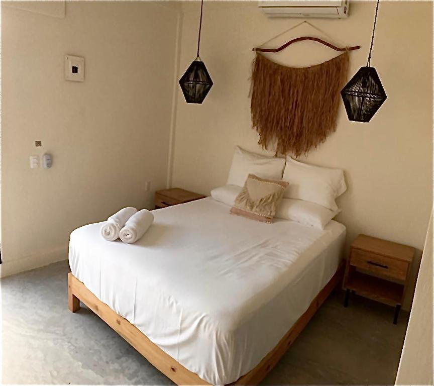 1 dormitorio con 1 cama con sábanas y almohadas blancas en Black flamingo en Holbox Island