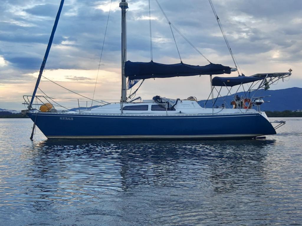 a blue sail boat sitting in the water at Veleiro Australis in Antonina