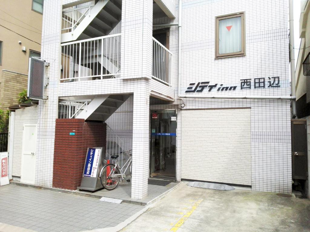 un edificio blanco con una bicicleta estacionada frente a él en City Inn Nishi Tanabe, en Osaka