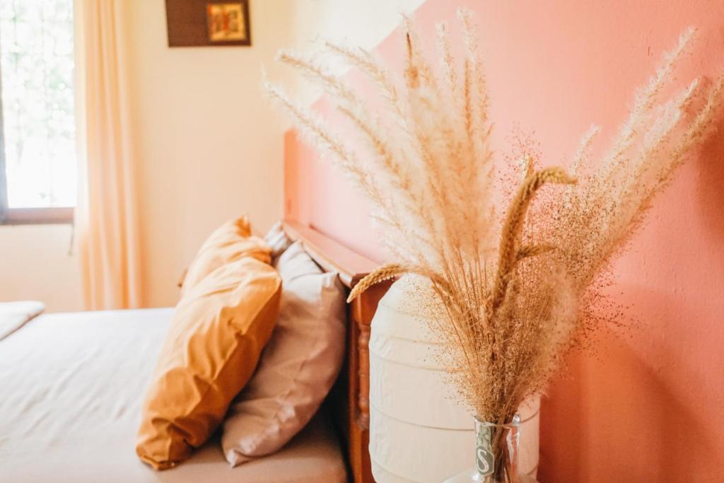 a bed with pillows and a vase with dry grass at Roemah Nelayan in Montongbuwoh