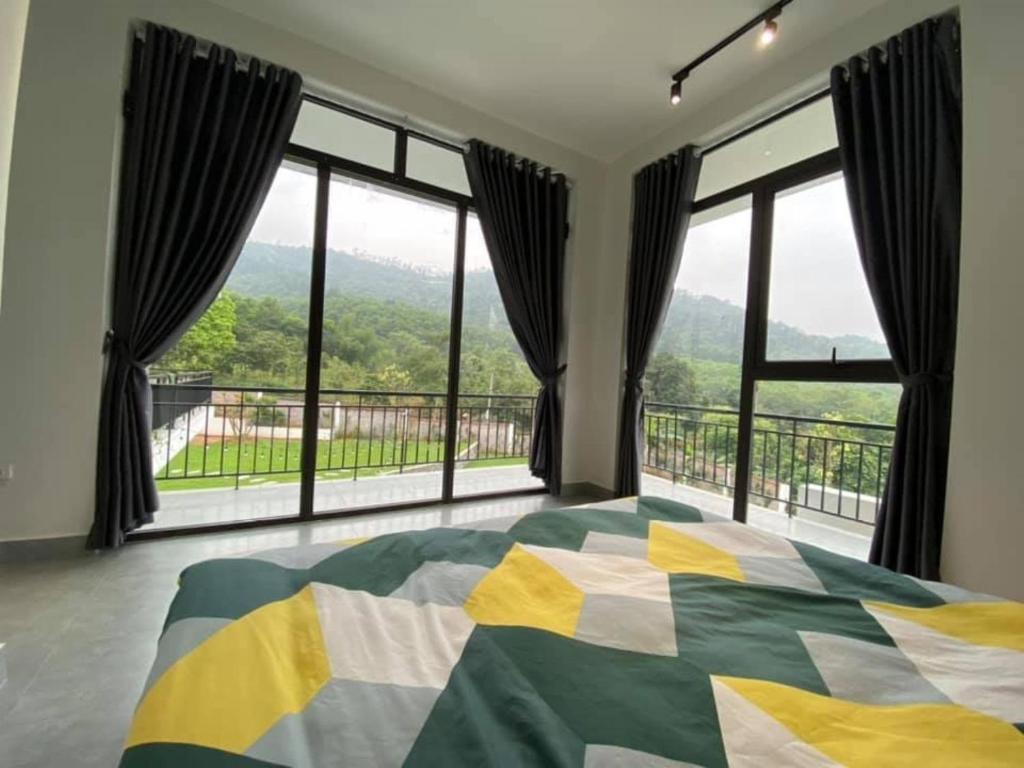 a bedroom with a large bed and large windows at Sun Hill Villa Ba Vì - Venuestay in Hanoi