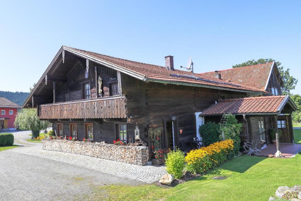 une grande maison en bois avec des fleurs devant elle dans l'établissement Roblhof, à Drachselsried