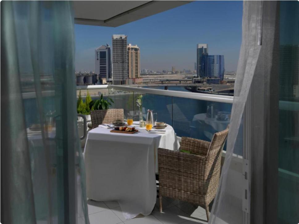 a table on a balcony with a view of the city at Canal Views Studio Apartment in Dubai