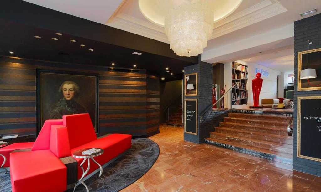 a lobby with red chairs and a painting of a woman at Hôtel de Brienne in Toulouse