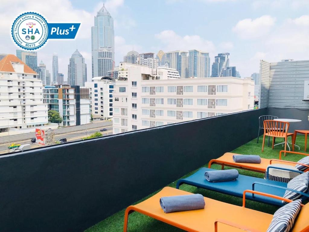 a balcony with tables and chairs and a city skyline at Alt Hotel Nana by UHG in Bangkok