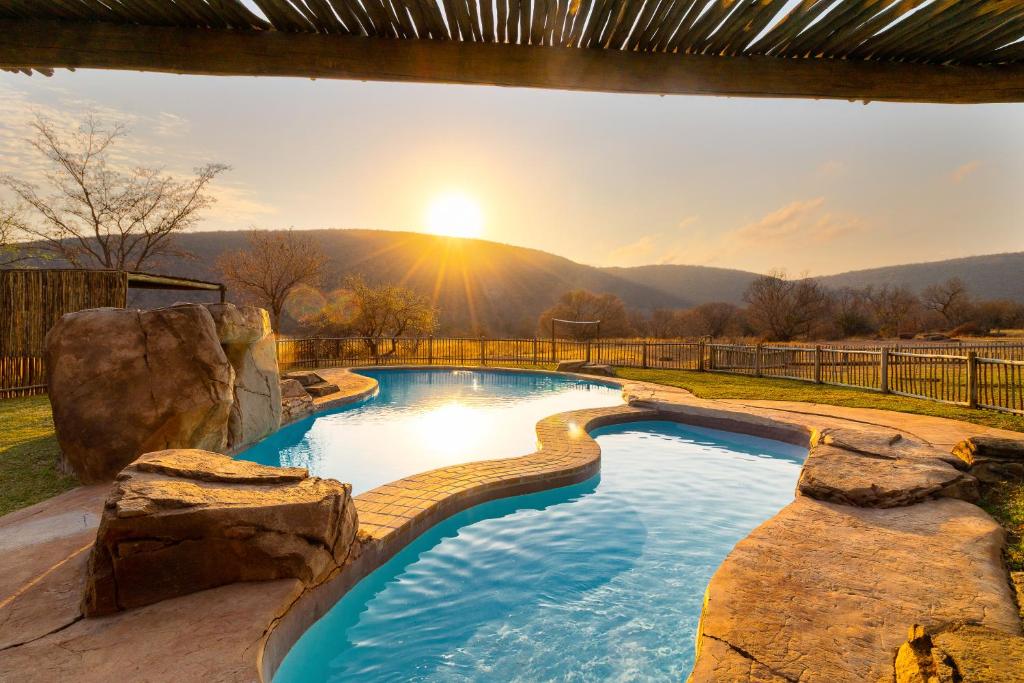a pool in a backyard with a view of the sunset at Lindani Game and Lodges in Vaalwater