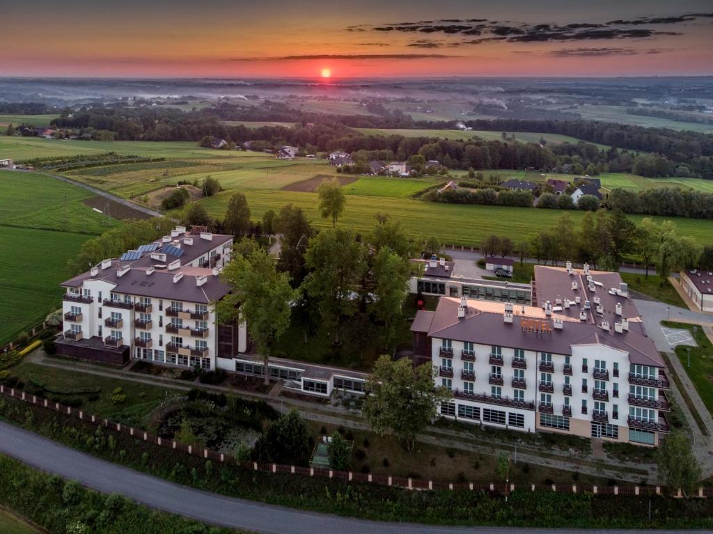una vista aérea de un edificio con una puesta de sol en el fondo en Hotel Radocza Park Business, en Radocza