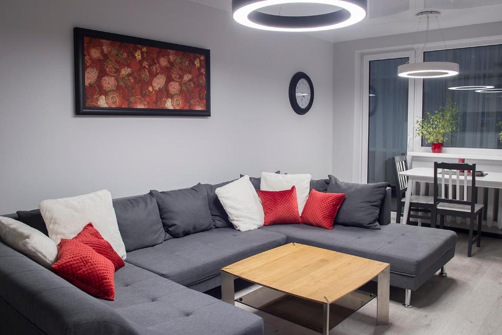 a living room with a gray couch with red pillows at Siauliai Apartments - Lieporiu in Šiauliai