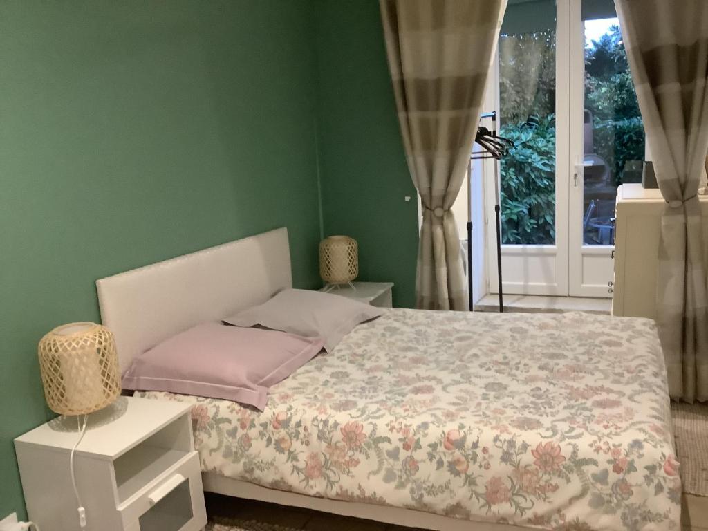 ein grünes Schlafzimmer mit einem Bett und einem Fenster in der Unterkunft Le Petit Chalet in Bagnoles de l'Orne