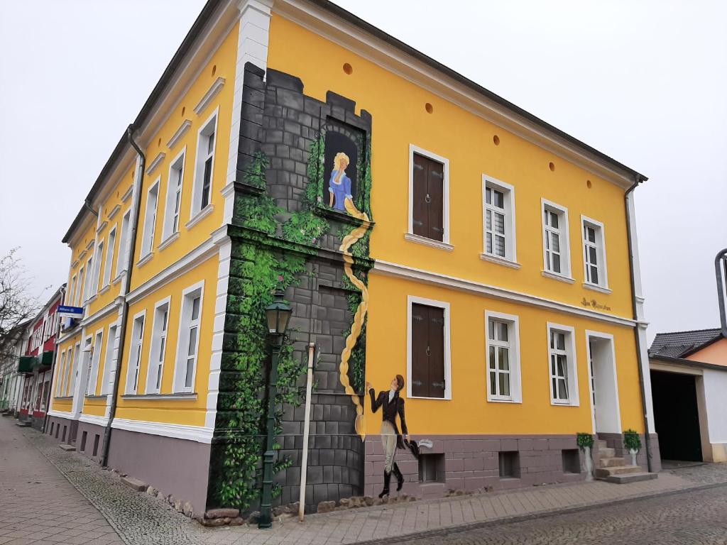 un edificio amarillo con una pintura a un lado en Ferienwohnung Zum Rapunzelturm en Schwedt