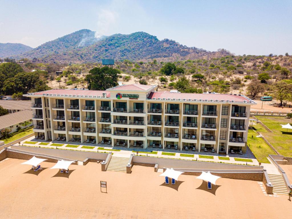 un grand bâtiment avec des parasols blancs devant lui dans l'établissement Sunbird Waterfront, à Salima