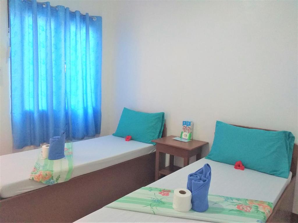 two beds in a room with blue curtains at Love Vega Hometel in El Nido
