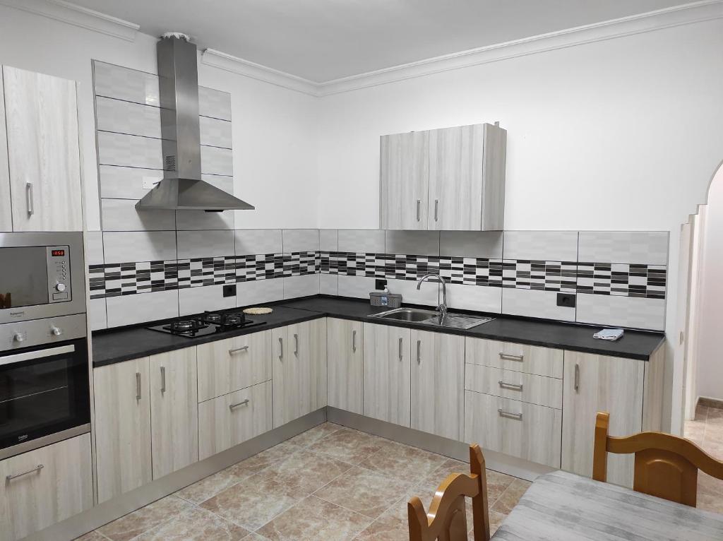 una cocina con armarios blancos y encimeras negras en Apartamento para familias, en Marzagán