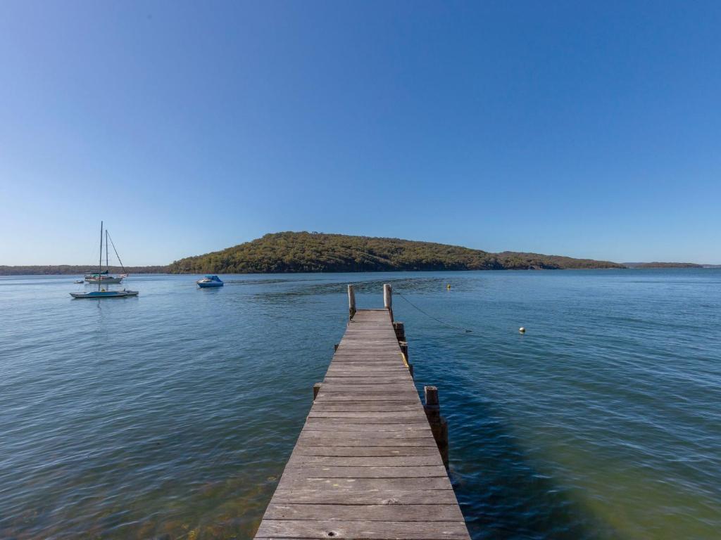 a wooden dock in the middle of the water with a boat at Wybalena in North Arm Cove
