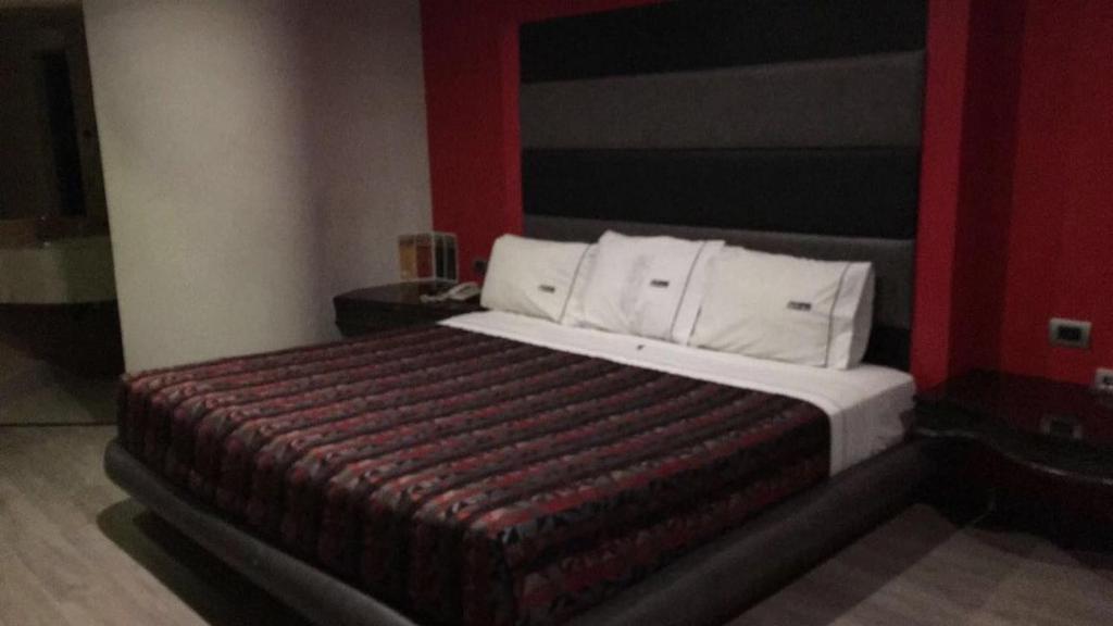 メヒカリにあるMotel Fronorteの赤い壁のベッドルーム1室(大型ベッド1台付)