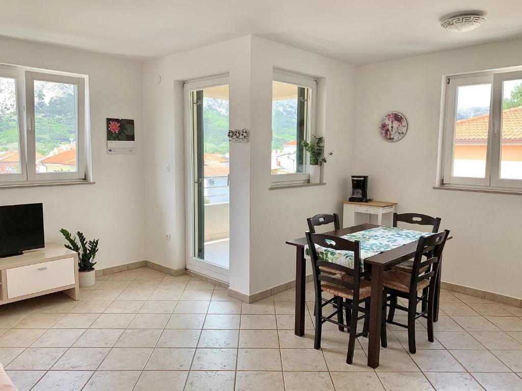 jadalnia ze stołem i krzesłami oraz telewizorem w obiekcie Apartments Happy Stay Center Baska w Bašce