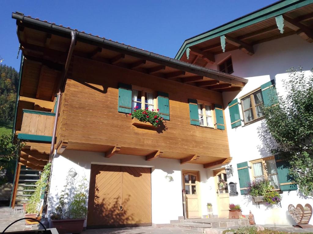 Casa con ventanas con persianas verdes y porche en Ferienwohnung Bergzeit, en Oberwössen