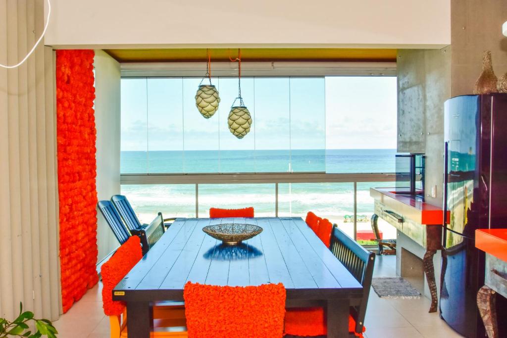 a dining room with a table and chairs and a view of the ocean at Apartamento frente mar na Praia do Santinho N880 in Florianópolis
