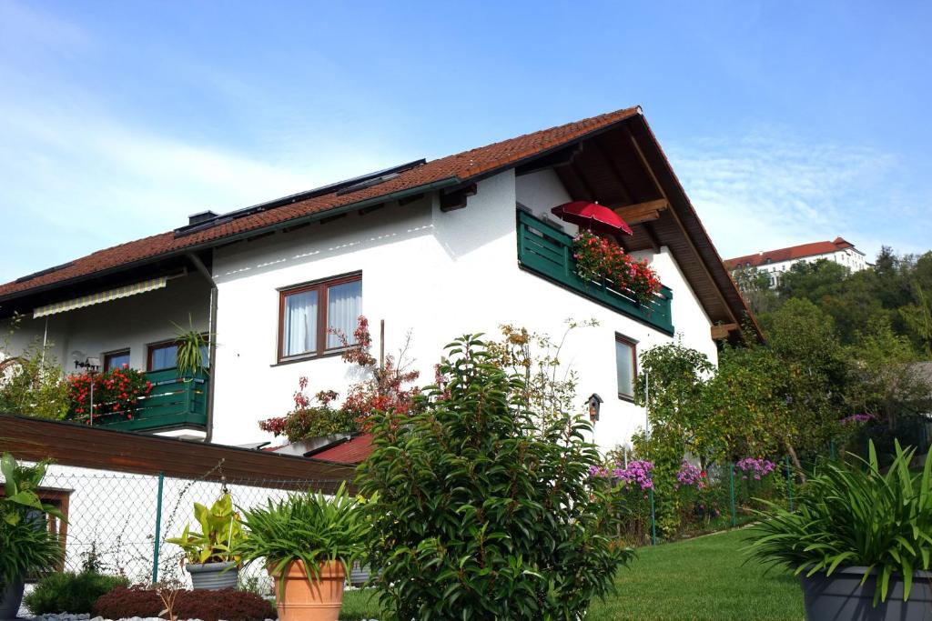 a white house with green shuttered windows and plants at Ferienwohnung Karch in Beilngries