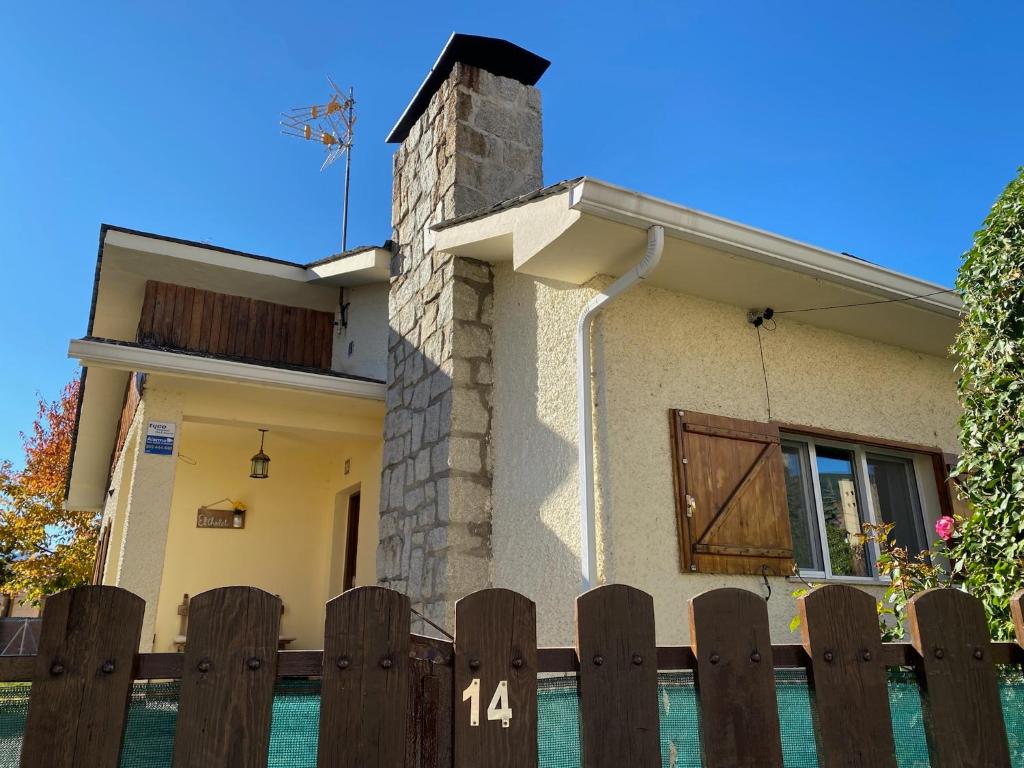 a house with a wooden fence in front of it at EL CHALET in Rascafría