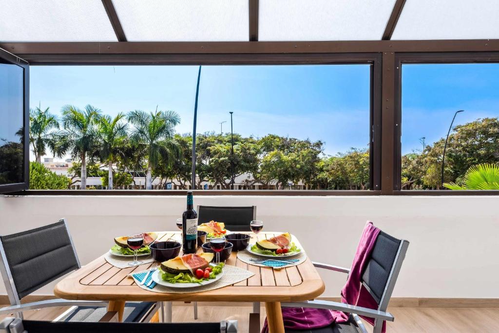 a table with food and wine on it in front of a window at Las Vistas Cristianos by Welcome Tenerife in Los Cristianos