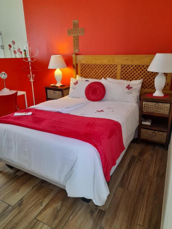 a bedroom with a large bed with a red wall at Die Rooi Windpomp in Polokwane