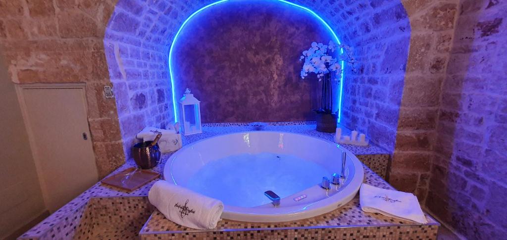 SINFONIE PUGLIESI LUXURY ROOM في توري: حمام مع حوض كبير مع إضاءة زرقاء
