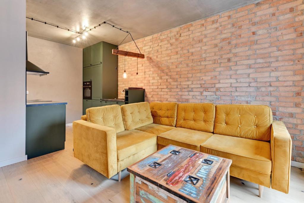 a living room with a couch and a brick wall at Grand Apartments - Browar Gdański - Design Apartment in Gdańsk