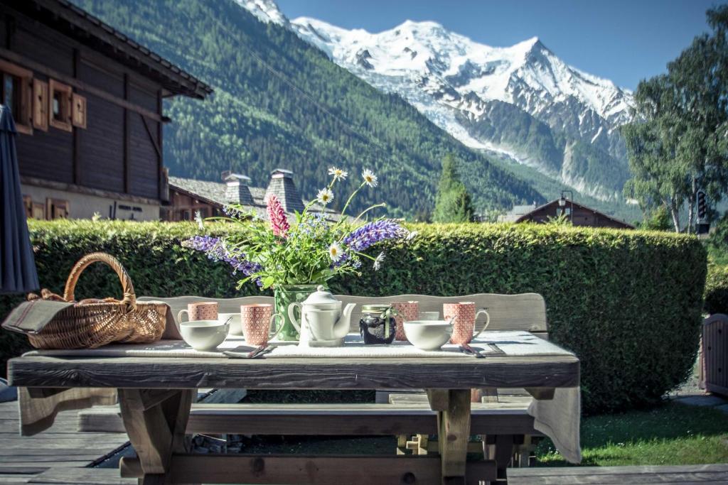 uma mesa de piquenique com flores com uma montanha em Paccard Locations Chamonix em Chamonix-Mont-Blanc