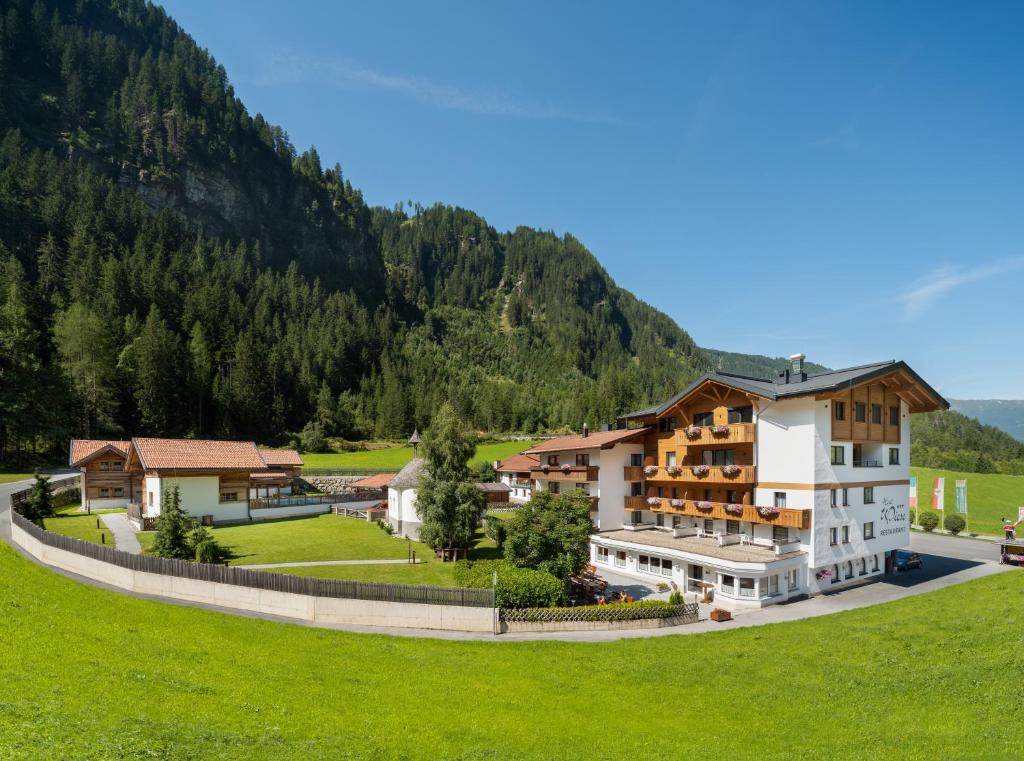 een gebouw in een veld met een berg op de achtergrond bij Hotel Wiese in Sankt Leonhard im Pitztal