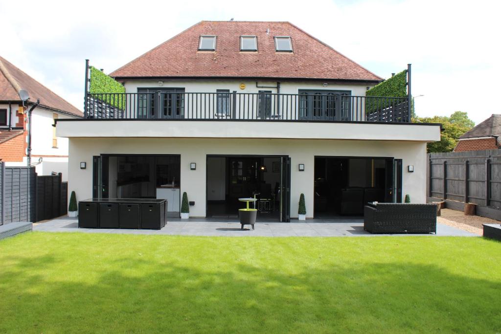 a house with a balcony on top of a yard at Modern Spacious House - Sleeps 16, Free Parking, Sun Terrace in Attleborough