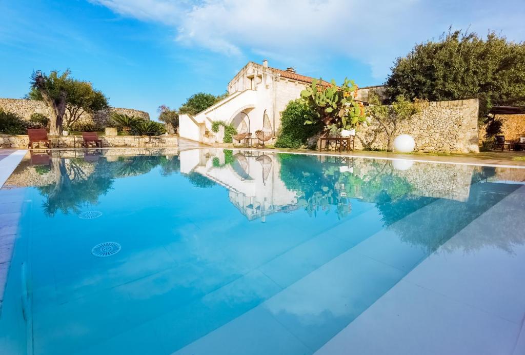 a swimming pool with a villa in the background at Don Agostino Relais Masseria in Martano