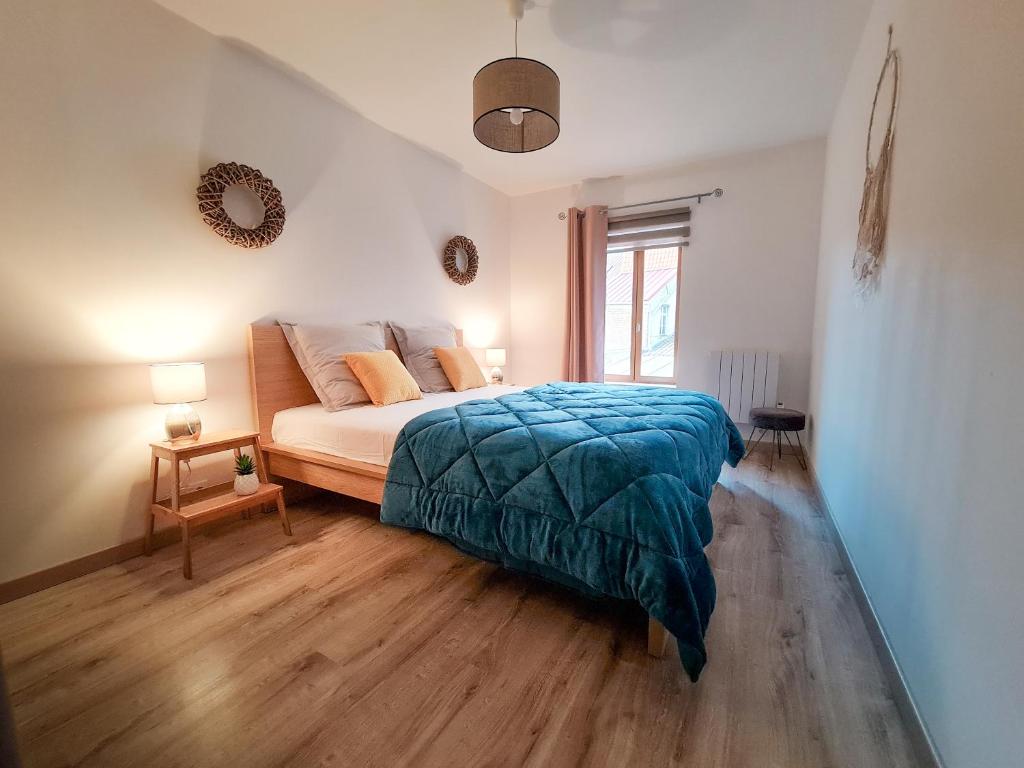 ein Schlafzimmer mit einem Bett mit einer blauen Decke darauf in der Unterkunft Fabrice et Frédérique in Carvin