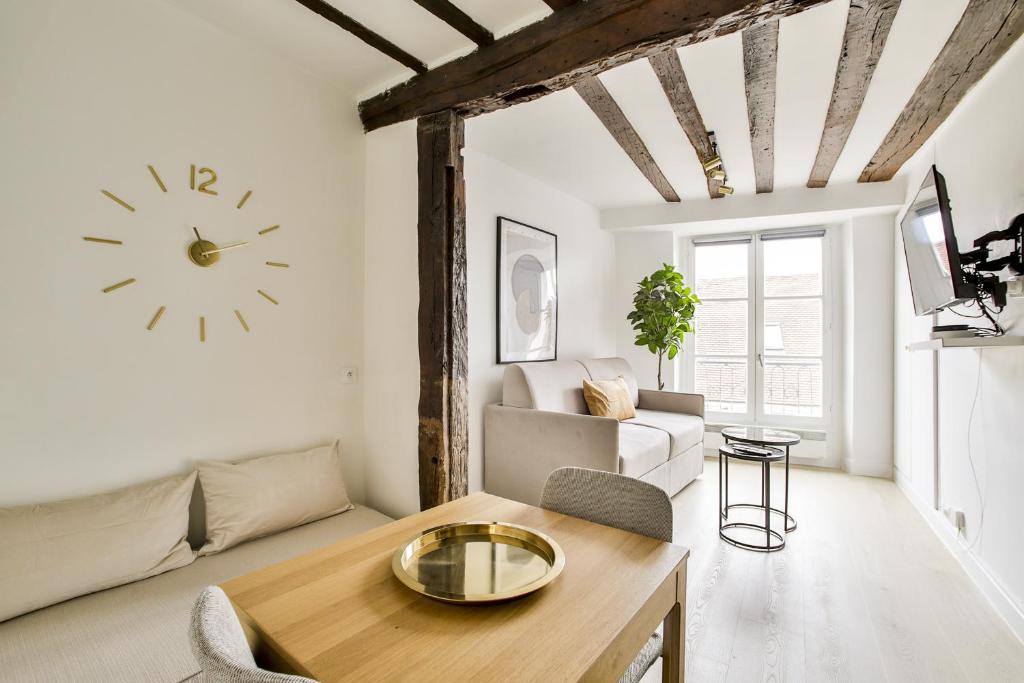 a living room with a couch and a clock on the wall at New&renovated cosy flat in The marais !!! 4pers in Paris