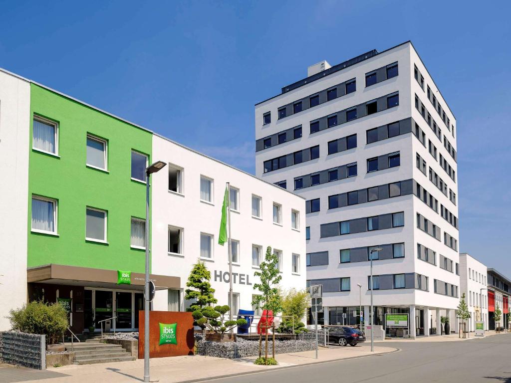 un edificio verde e bianco accanto a una strada di ibis Styles Arnsberg Sauerland a Neheim-Hüsten