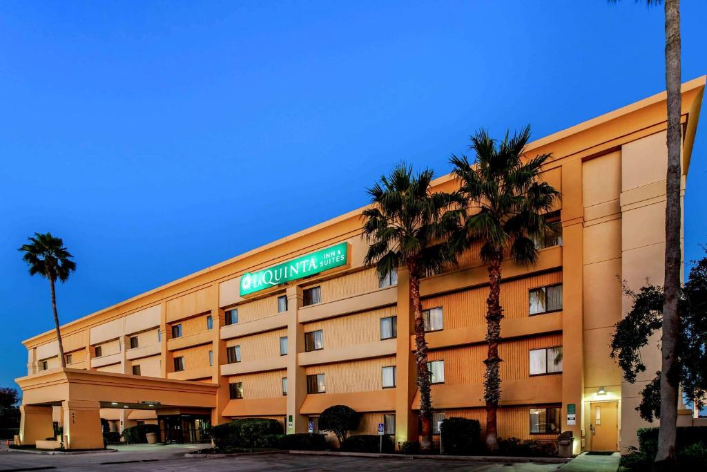 a hotel with palm trees in front of a building at La Quinta by Wyndham Houston Baytown East in Baytown