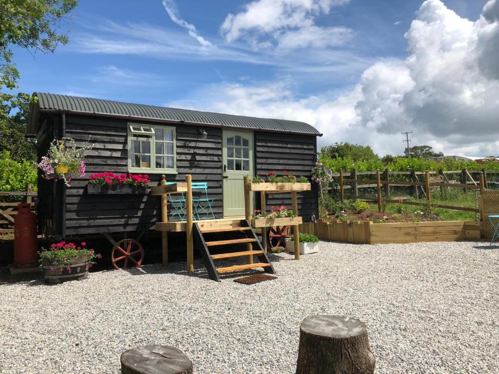a tiny house in a yard with a garden at Willow Brook Shepherd Hut in Sidmouth