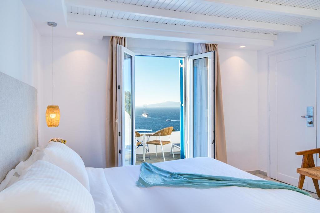 Hotel Madalena في مدينة ميكونوس: غرفة نوم مع سرير وإطلالة على المحيط