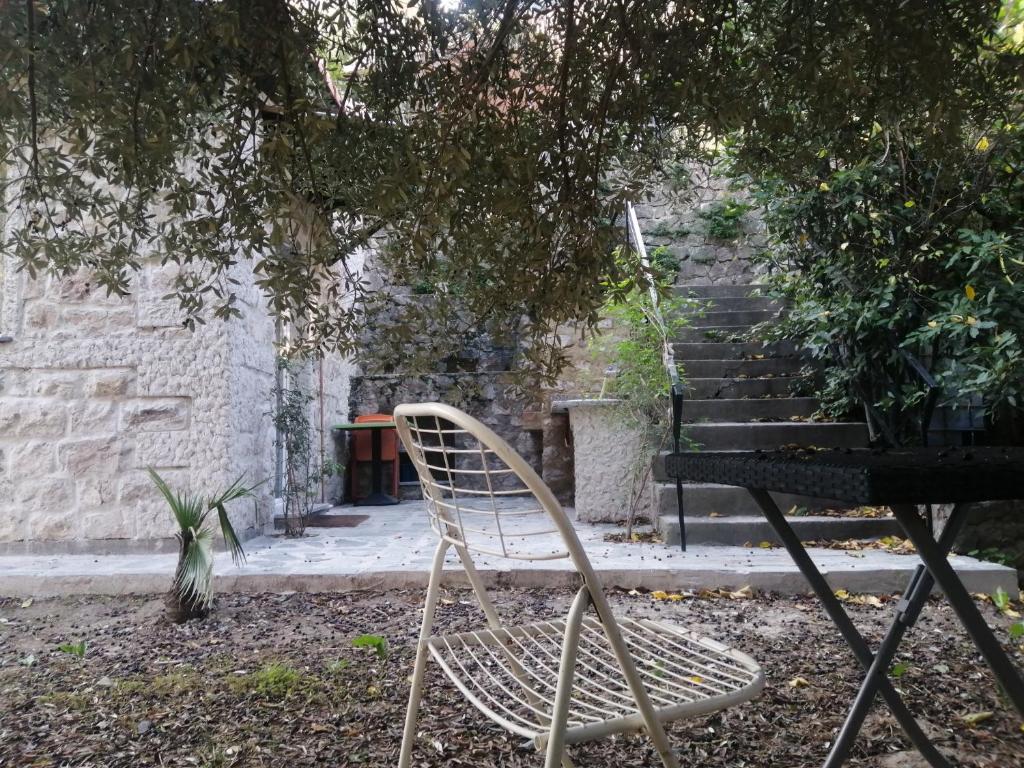 a white chair sitting under a tree next to a staircase at Emplacement idéal pour cette Maisonnette avec jardin et cuisine d'été in Roquebrune-Cap-Martin