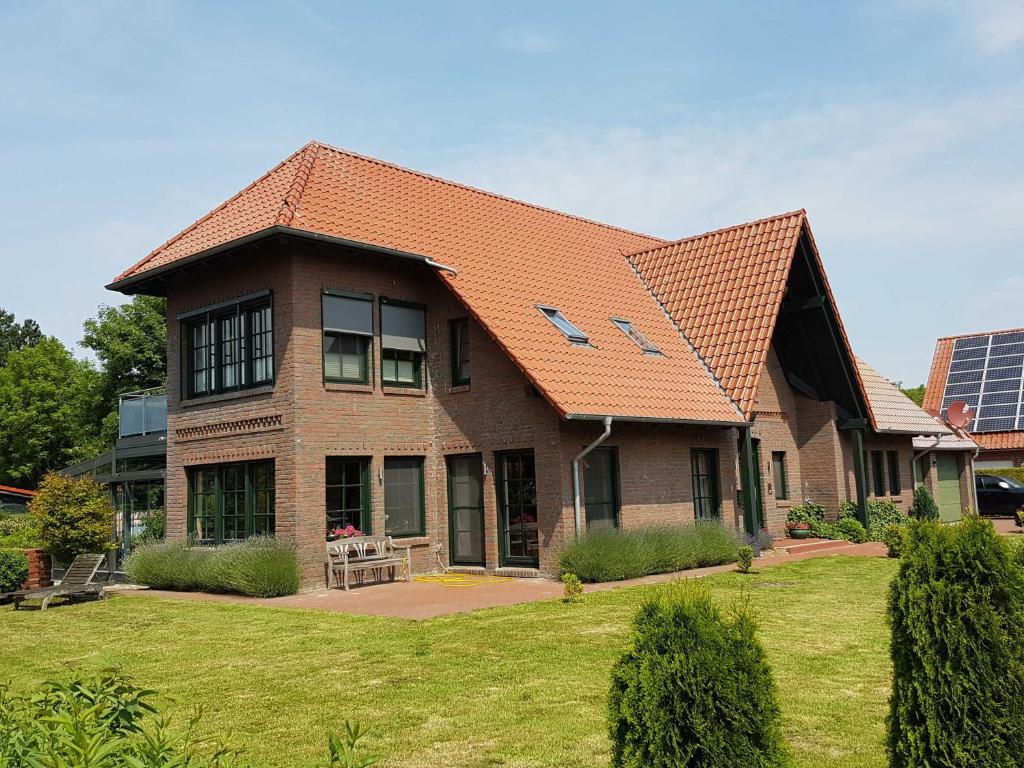 a large brick house with an orange roof at Ferienwohnungen Haus Elena 45241 in Ditzum