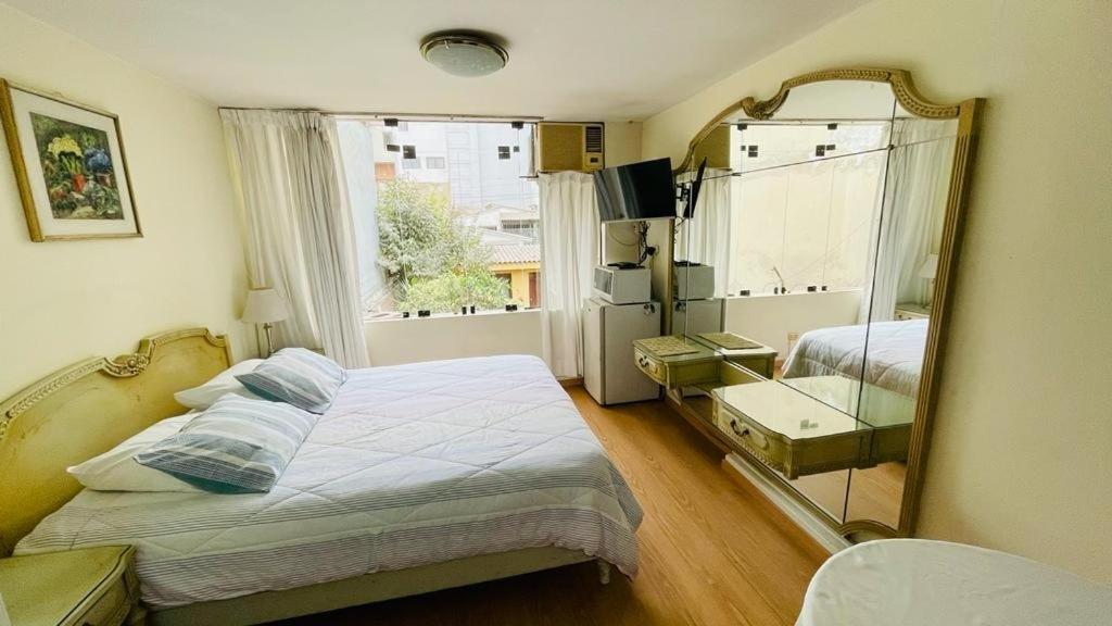 a small bedroom with a bed and a mirror at Villas Del Sol Bed & Breakfast in Lima